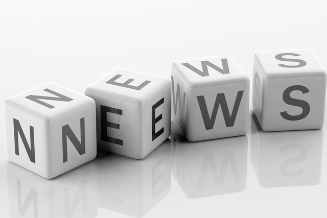 Vier Würfel mit Buchstaben statt Ziffern liegen auf einer glatten Oberfläche und bilden das Wort NEWS