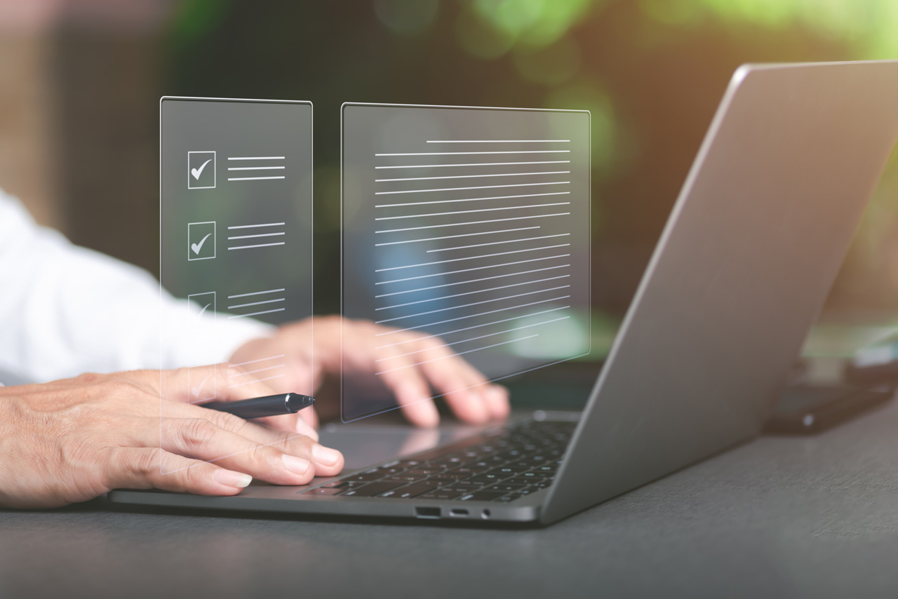 Auf einem Tisch steht ein Laptop. Ein Mann gibt etwas ein. In der rechten Hand hält er einen Stift. Im Hintergrund des Bildes sieht man virtuelle Listen. Das Bild steht für die Schritt für Schritt Anleitung der digitalen Baugenehmigung.